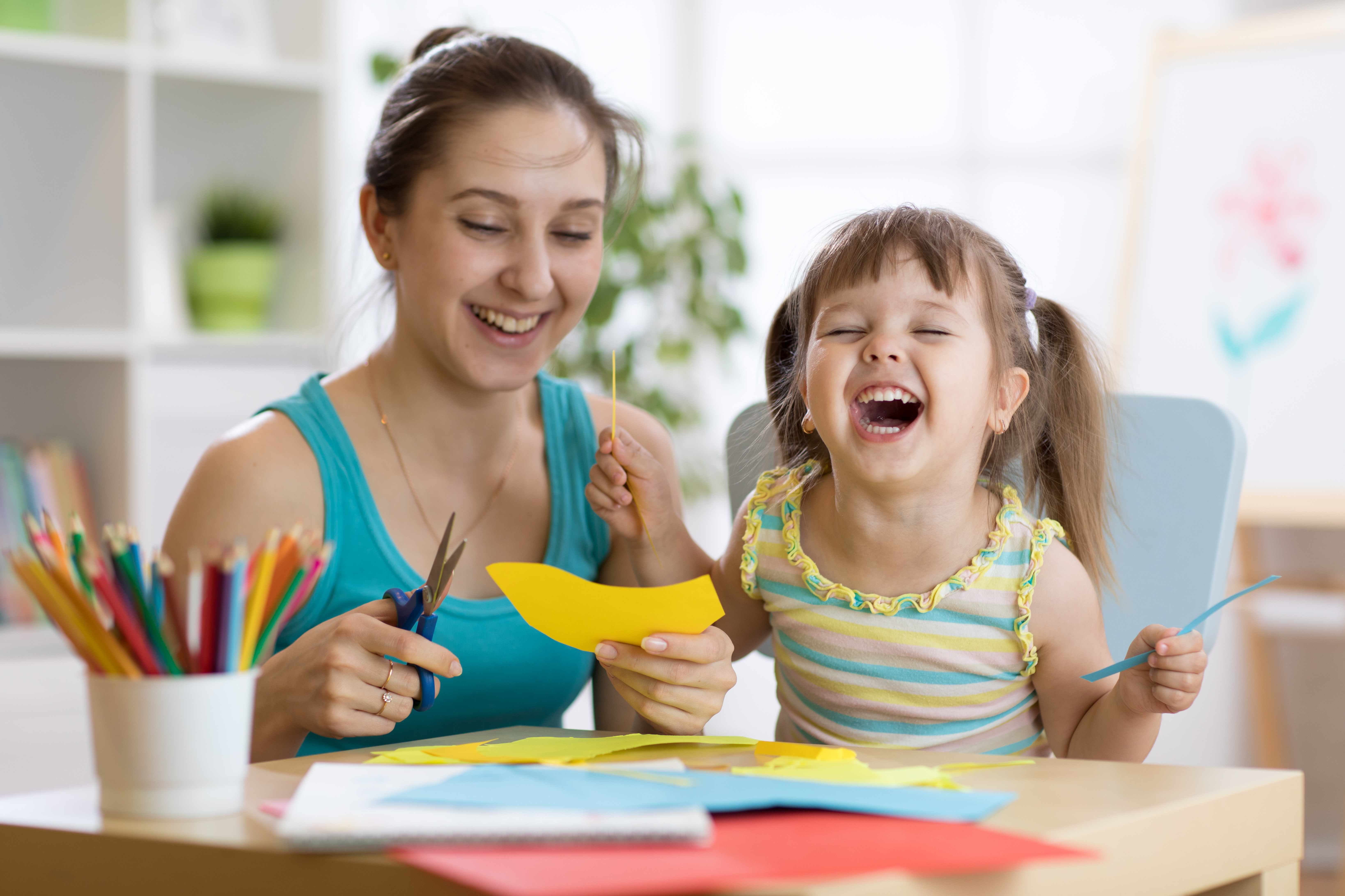 Mother and child work together on a craft as the child laughs out loud.