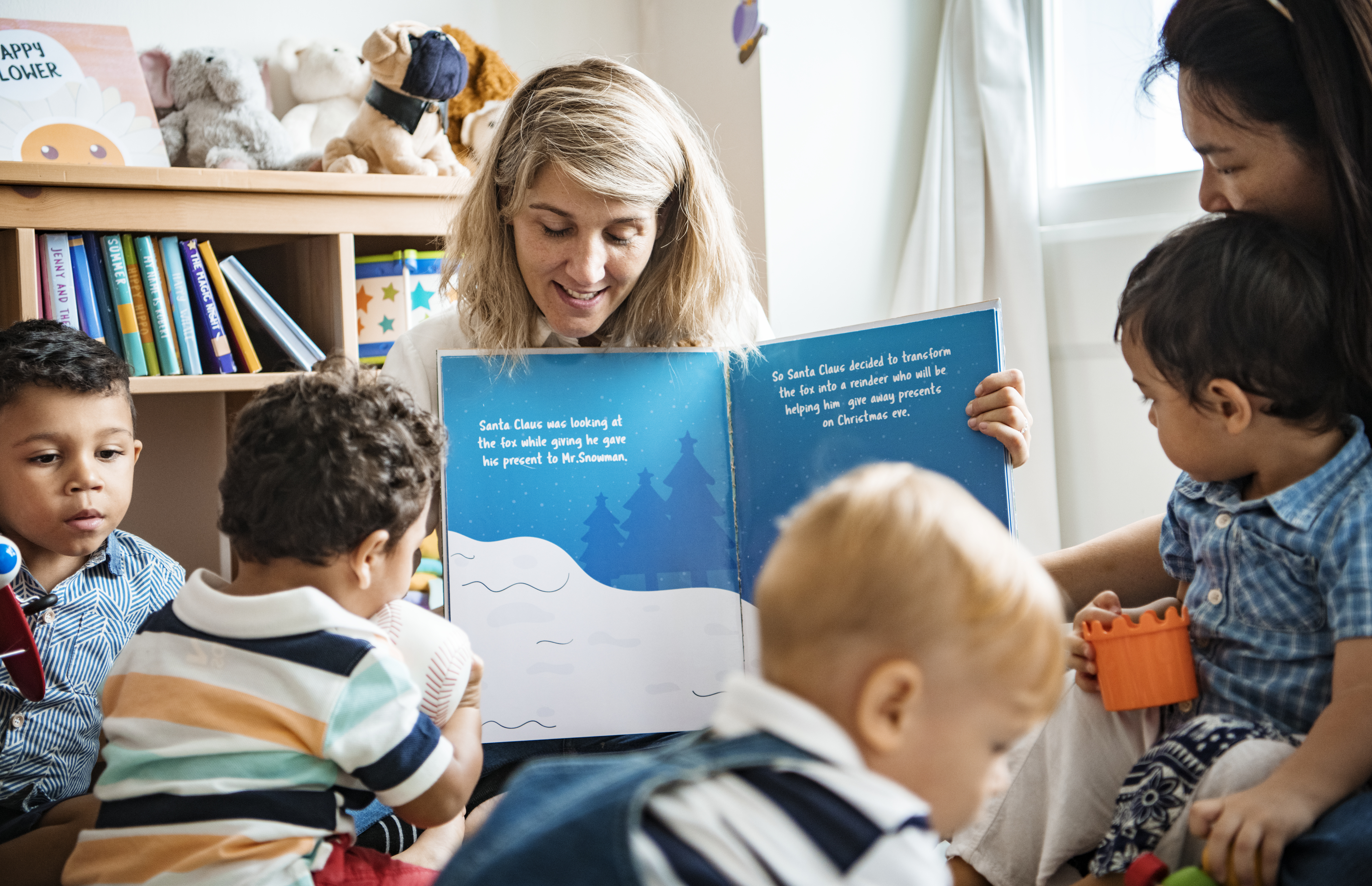 Woman reads picture book to room full of children.