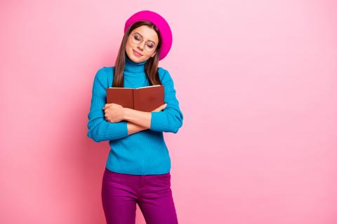 Trendy teenager clutches a book to her chest.