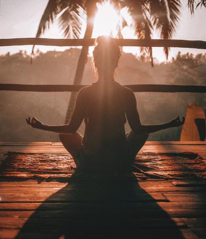 Female meditating while facing the sun.